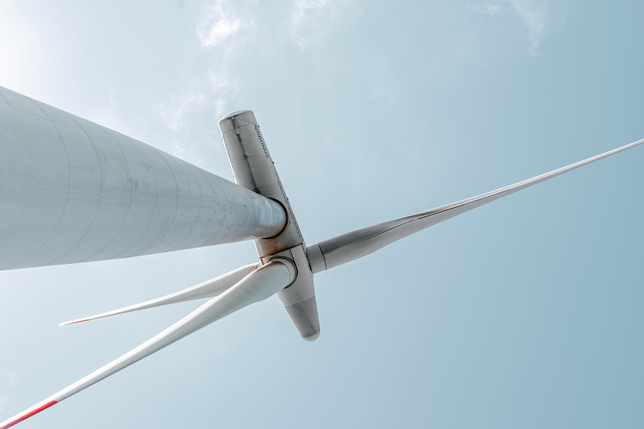 service-04 Looking up at a majestic wind turbine under a clear blue sky, showcasing renewable energy innovation.